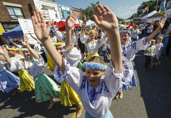 A boy in a green shirt waves a Ukrainian flag and holds a white balloon